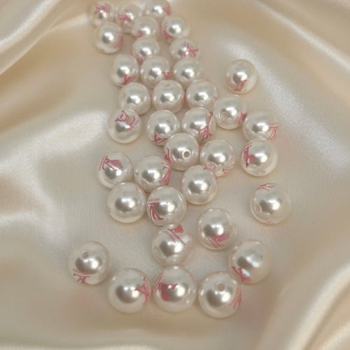 White pearl beads with pink markings, ideal for DIY jewelry making and handmade crafts on satin fabric