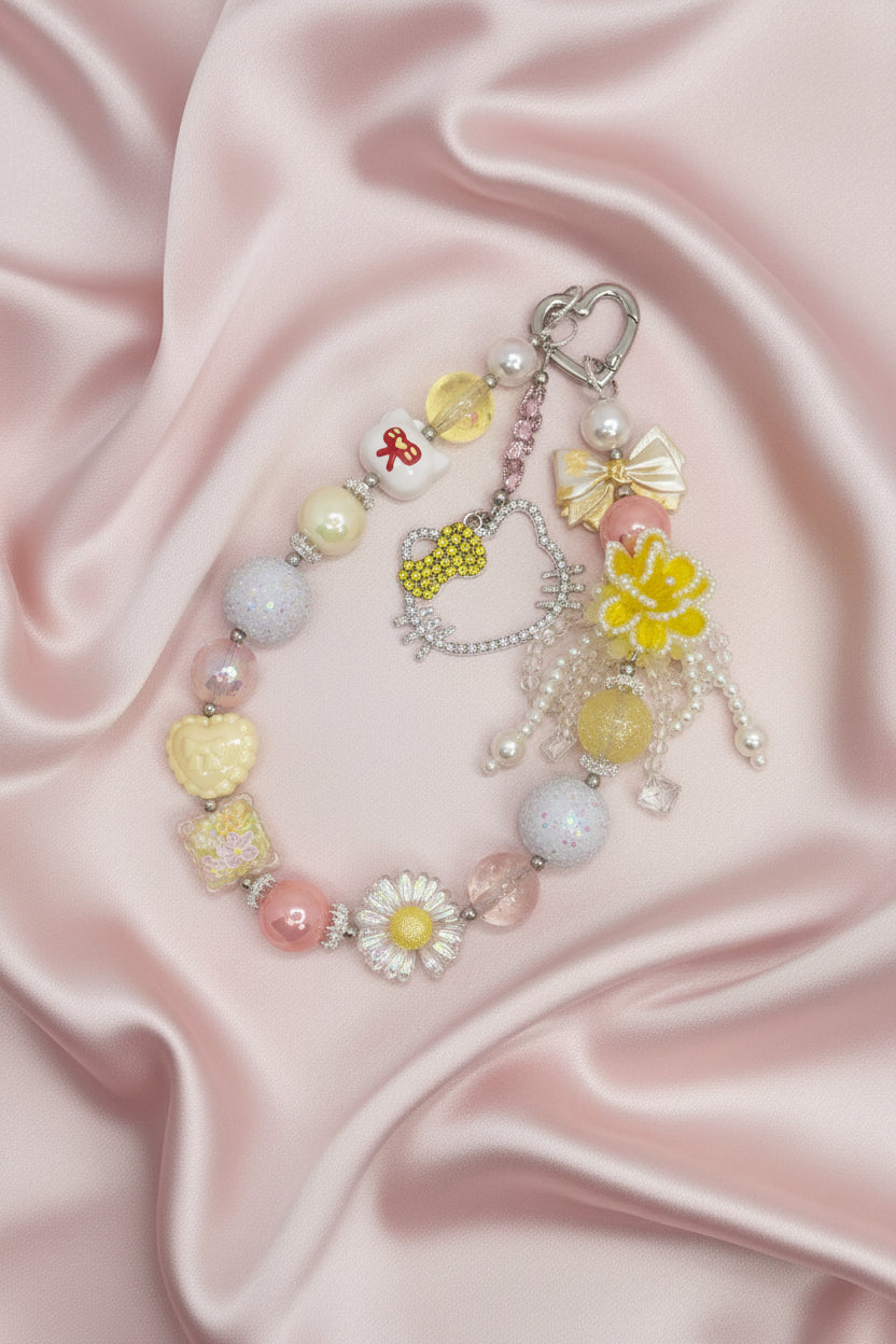 Handmade beaded charm bracelet with pastel beads, flowers, and bows on pink satin background