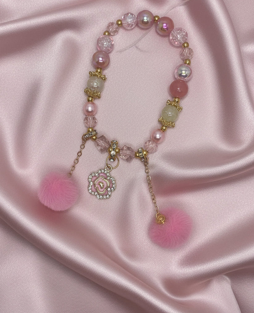 Pink beaded bracelet with floral charm and pom poms, handmade DIY accessory on satin