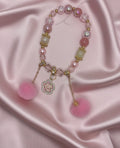 Pink beaded bracelet with floral charm and pom poms, handmade DIY accessory on satin