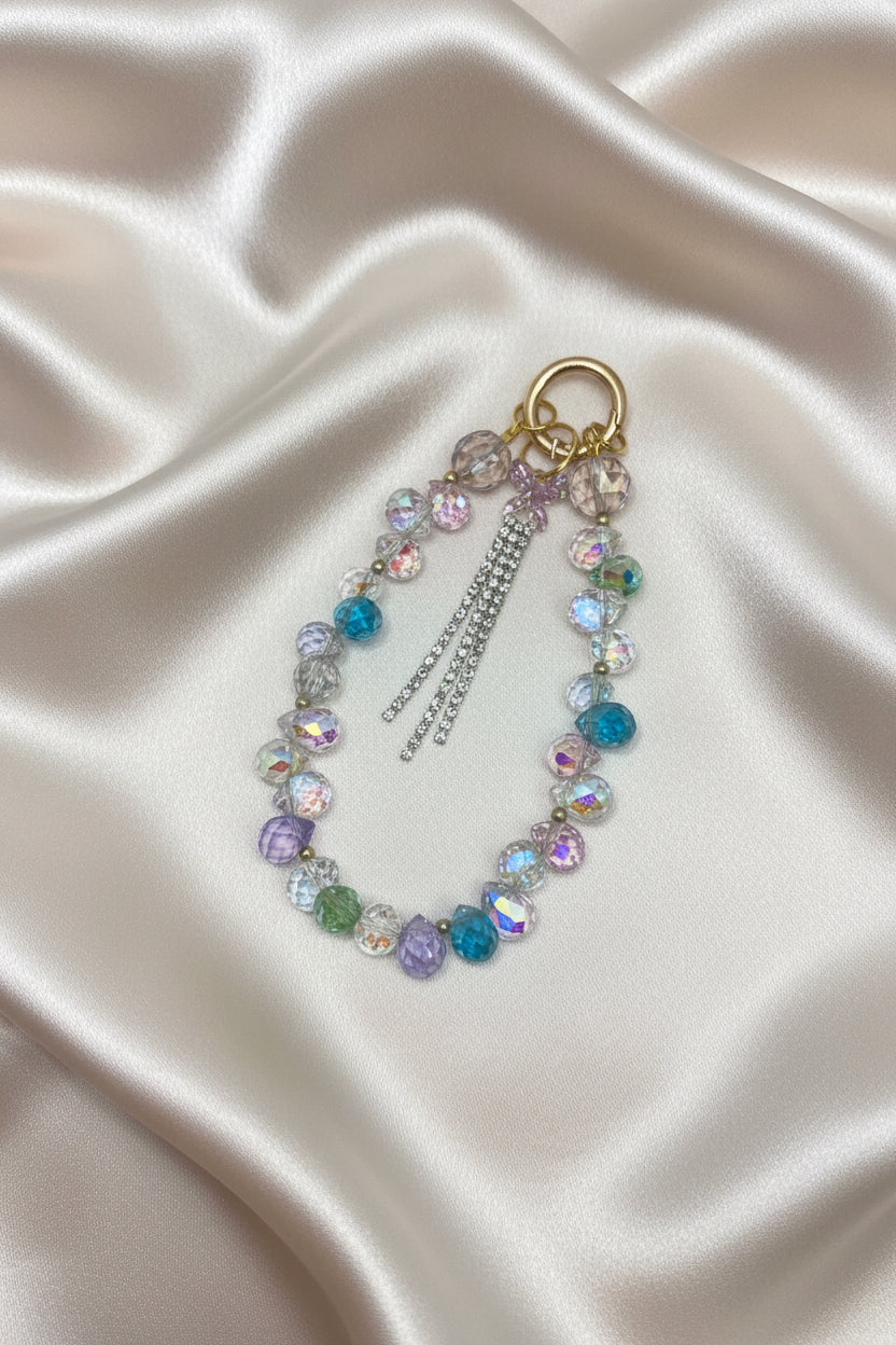 Handmade beaded keychain with iridescent crystals and tassels on satin, perfect for DIY accessories.