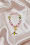 Handmade beaded bracelet with pink beads, gold bee charm, and rose pendant on satin background