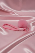 Pink fluffy pom pom hair tie with keychain on satin fabric, handmade accessory for crafts