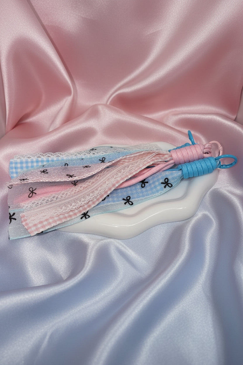 Pastel ribbon tassels with bow prints, lace trim, and twisted cord ends on satin fabric for DIY crafts