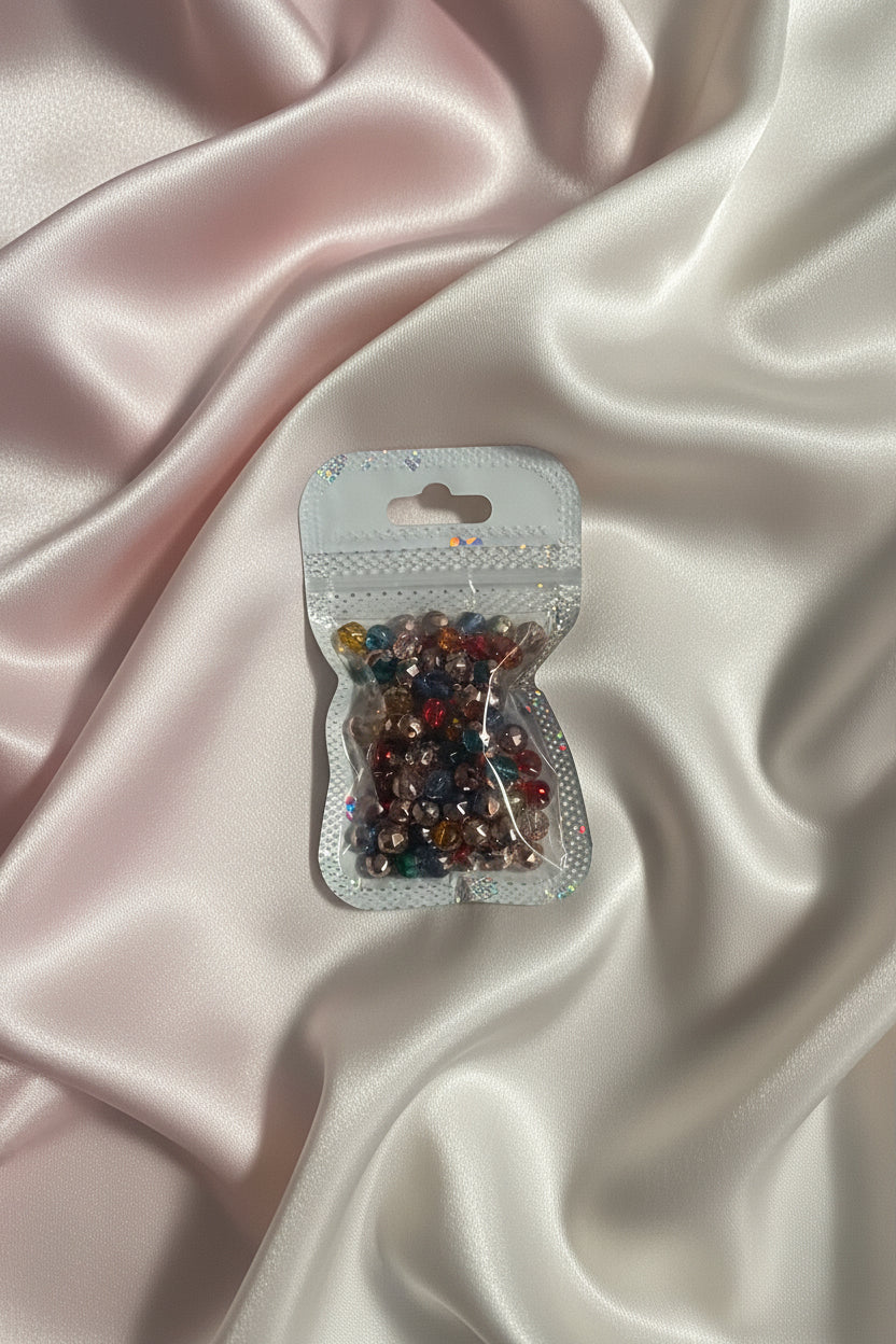 Colorful faceted beads in clear package on soft satin fabric, perfect for DIY jewelry making and crafts