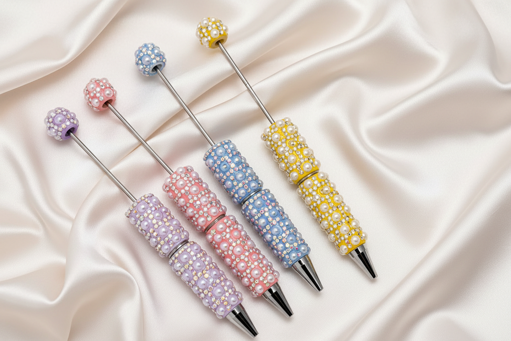 Handmade beaded pens in pastel colors with pearls and rhinestones, perfect for DIY crafts and stationery.