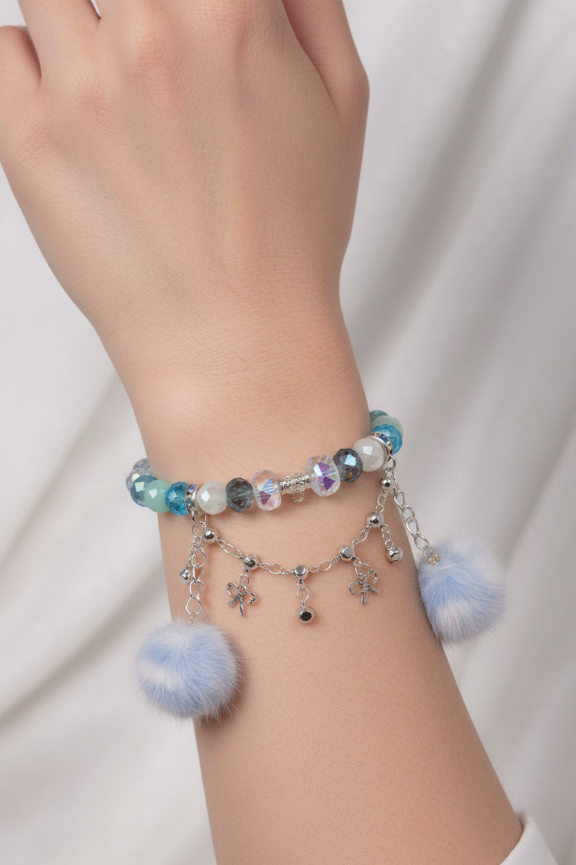 Handmade beaded bracelet with blue pom poms and flower charms, perfect for DIY accessories and crafts.