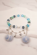 Handmade beaded bracelet with blue, mint, and iridescent beads, silver charms, and fluffy pom poms