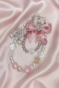 Handmade beaded necklace with pink bow, pearls, and crystal charms on satin background