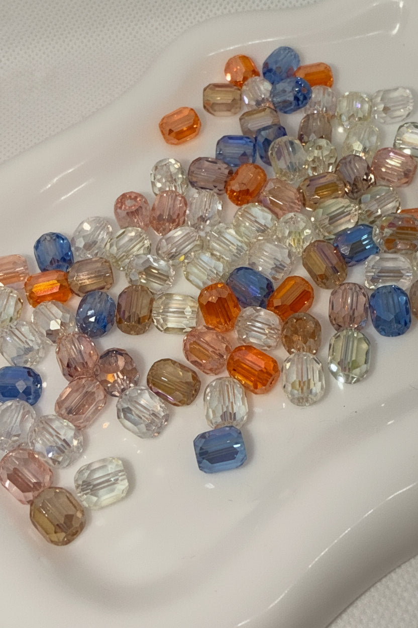 Assorted faceted glass beads in blue, orange, pink, and clear for DIY jewelry making and crafts