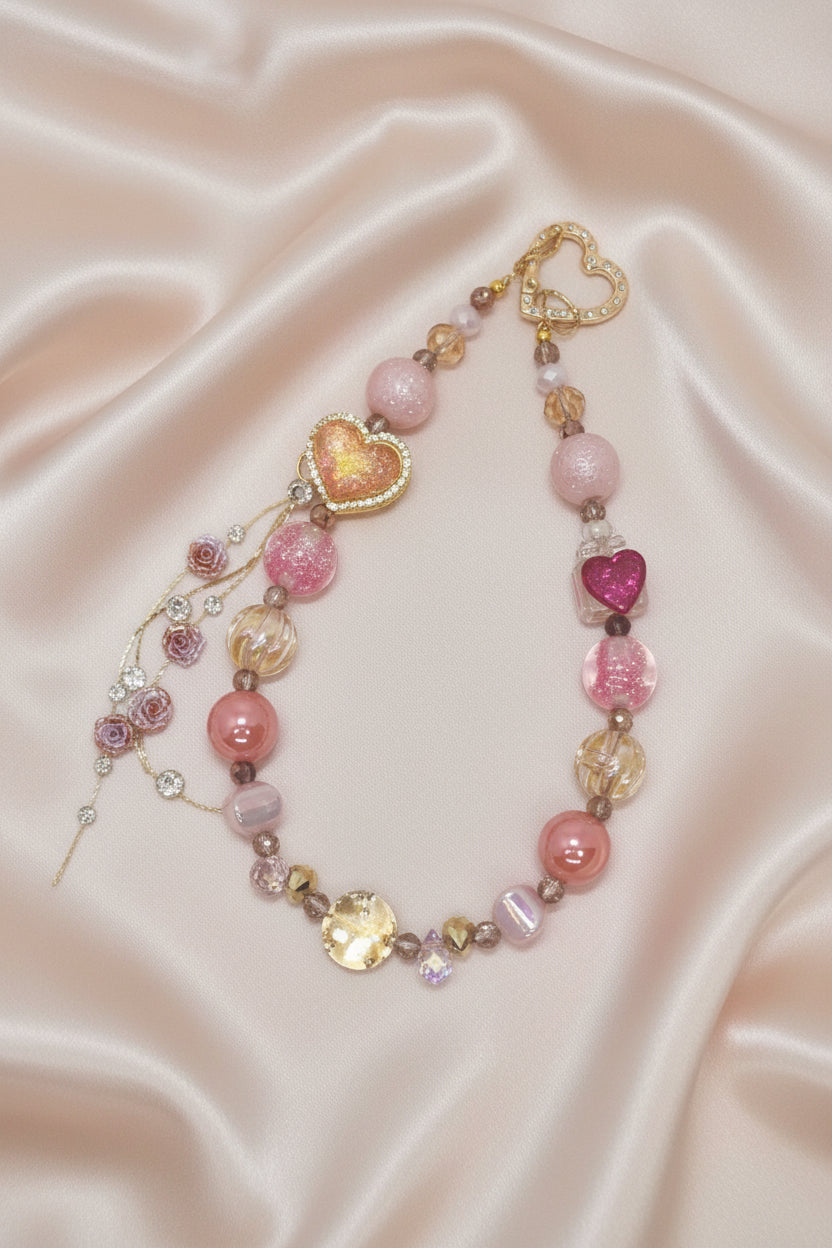 Handmade beaded necklace with pink hearts, glitter beads, and rose charms on satin, perfect for DIY accessories.