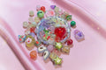 Colorful handmade resin beads and charms for DIY jewelry making on pink satin background