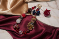 Handmade beaded necklace with red, gold, and blue crystals on velvet fabric