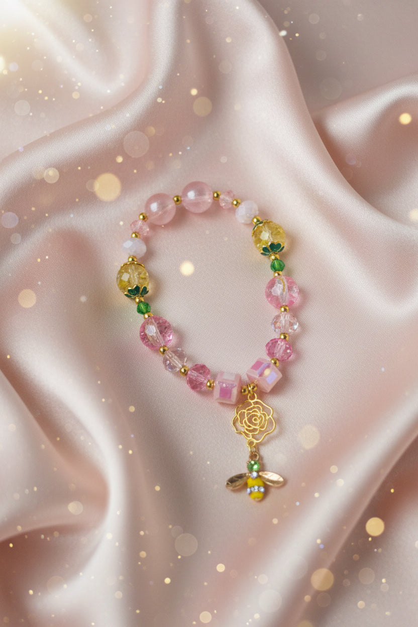 Handmade beaded bracelet with pink, yellow beads, gold rose, and bee charm on satin, perfect for DIY crafts
