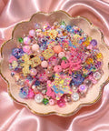 Colorful kawaii beads and charms in a pink scalloped dish for DIY jewelry making and crafts