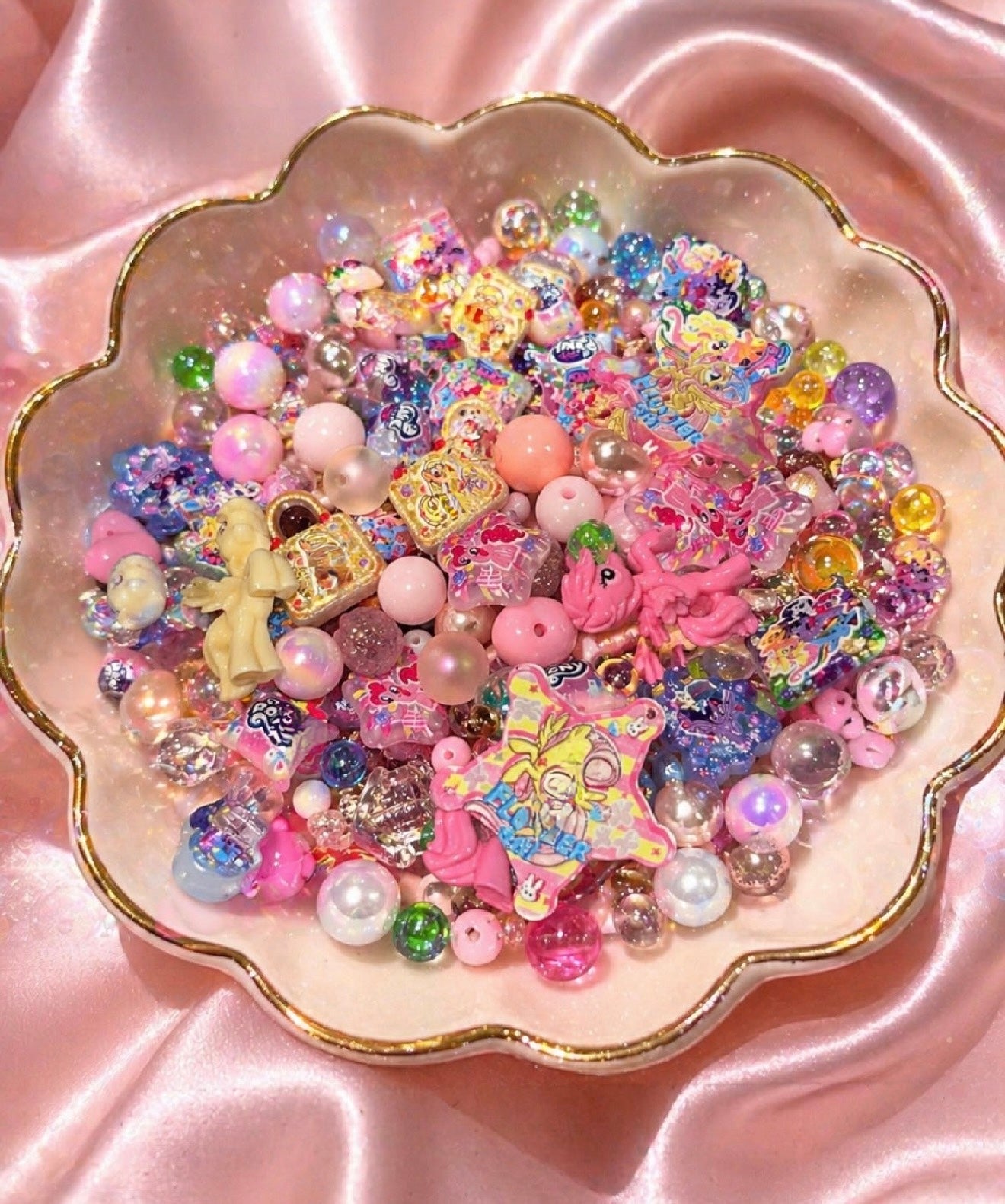 Colorful kawaii beads and charms in a pink scalloped dish for DIY jewelry making and crafts