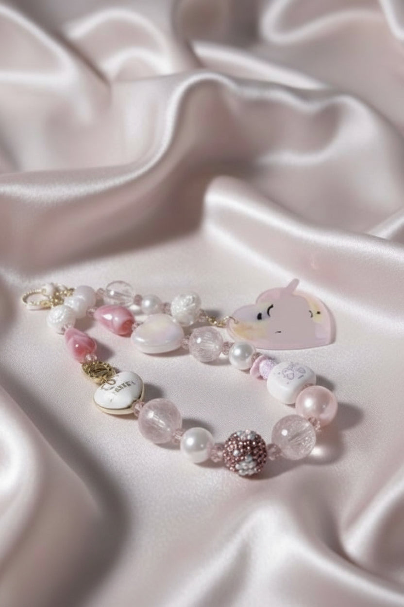 Handmade pink beaded necklace with unicorn charm, pearls, and crystal beads on satin fabric