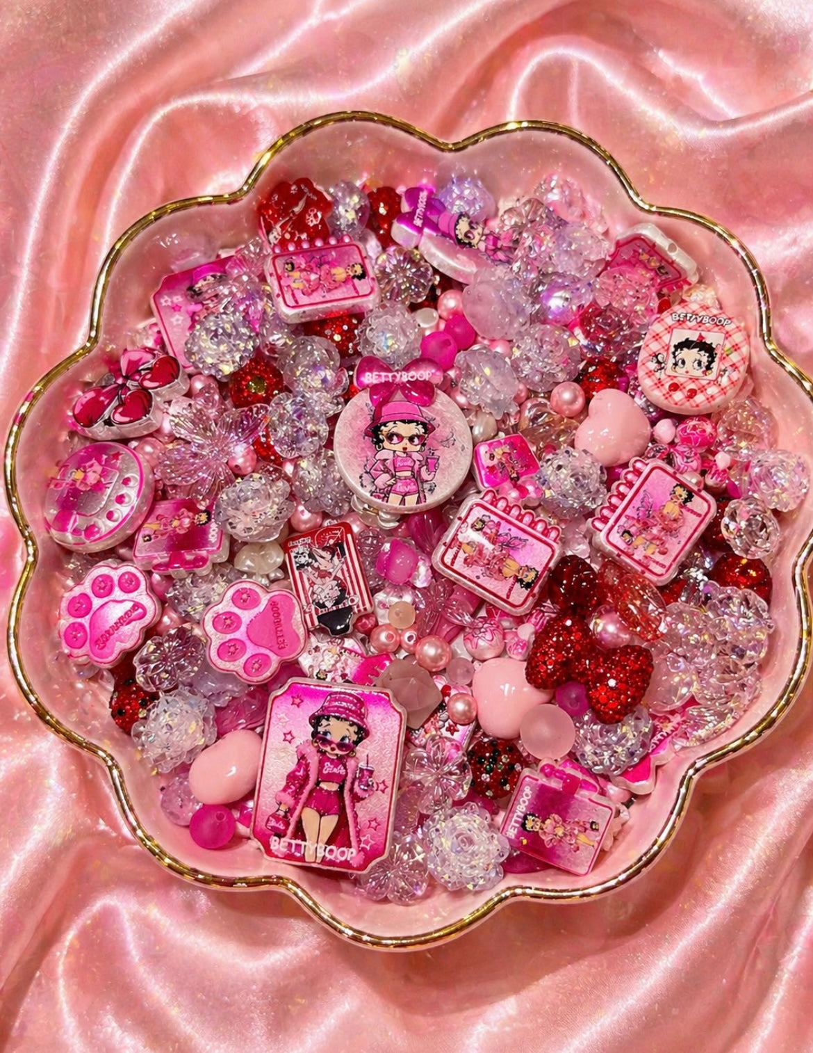 Pink Betty Boop beads and charms in a gold-rimmed bowl for DIY jewelry making