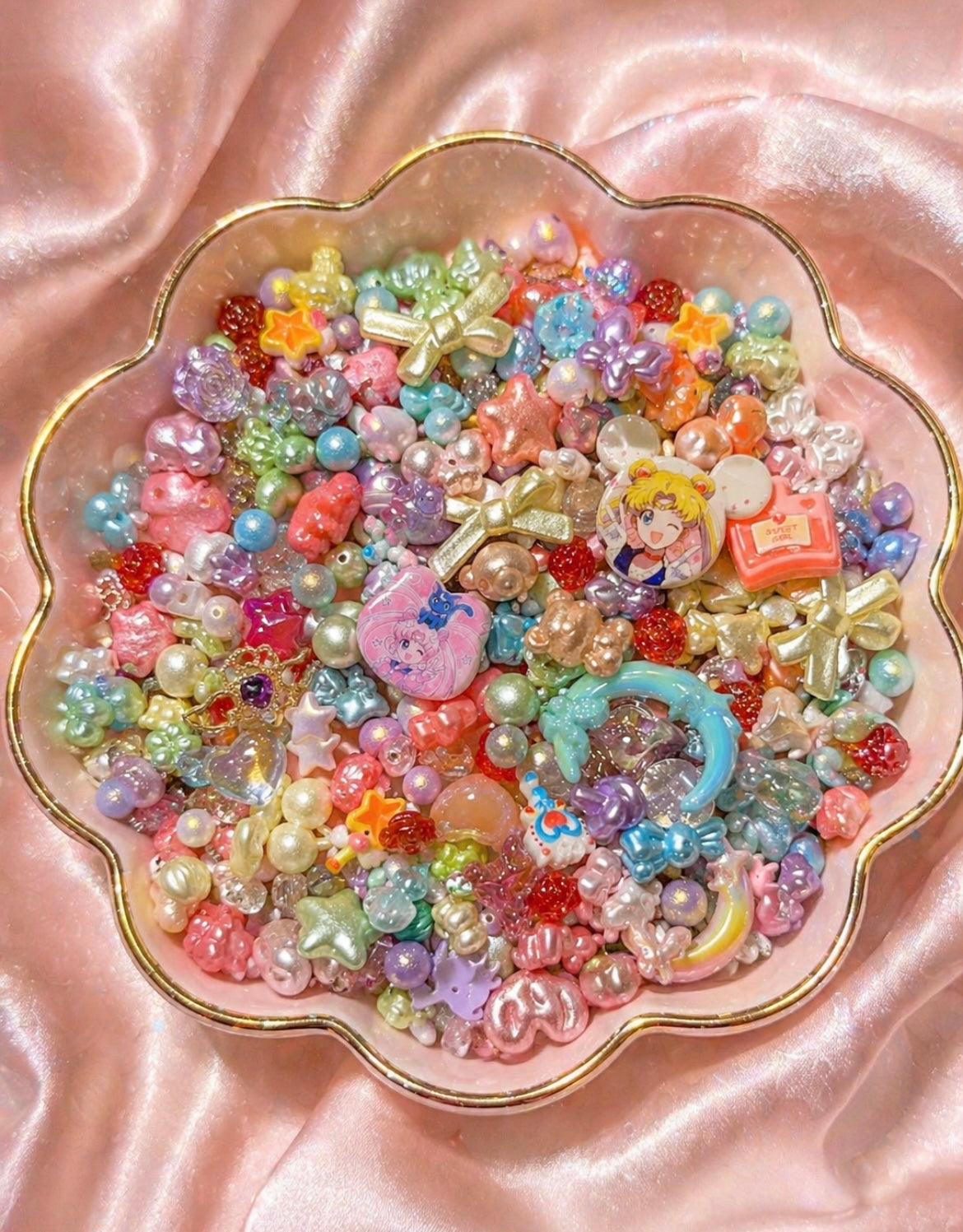 Colorful pastel beads, charms & DIY craft supplies in a pink scalloped dish for handmade jewelry making