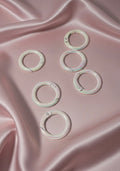 Iridescent snap rings for DIY jewelry making on pink satin fabric