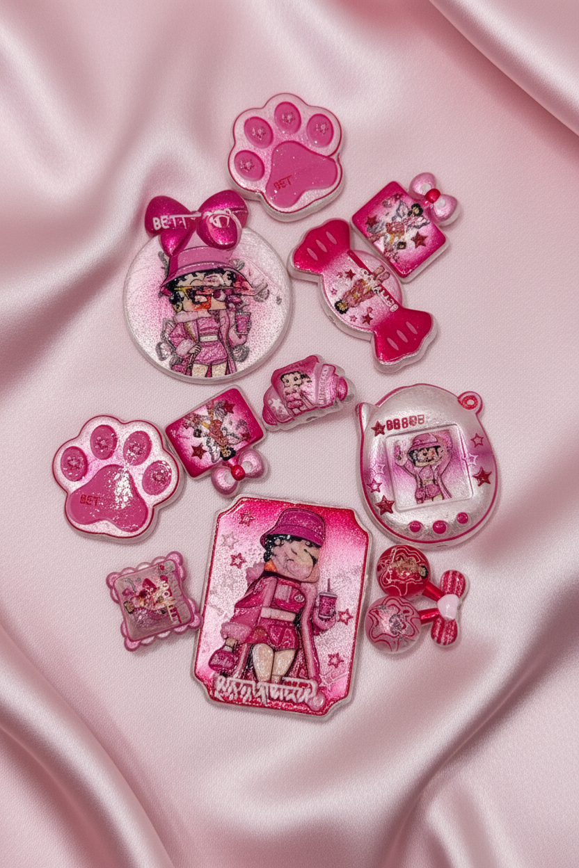 Pink glittery Betty Boop charms, paw prints, and accessories on satin fabric for DIY crafts