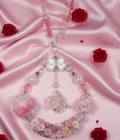 Handmade beaded necklace with pink flowers, bow charm, and crystal beads on satin, perfect for DIY accessories.