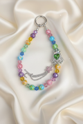 Rainbow beaded keychain with green heart charm, crystal accents, and silver crown pendant on satin