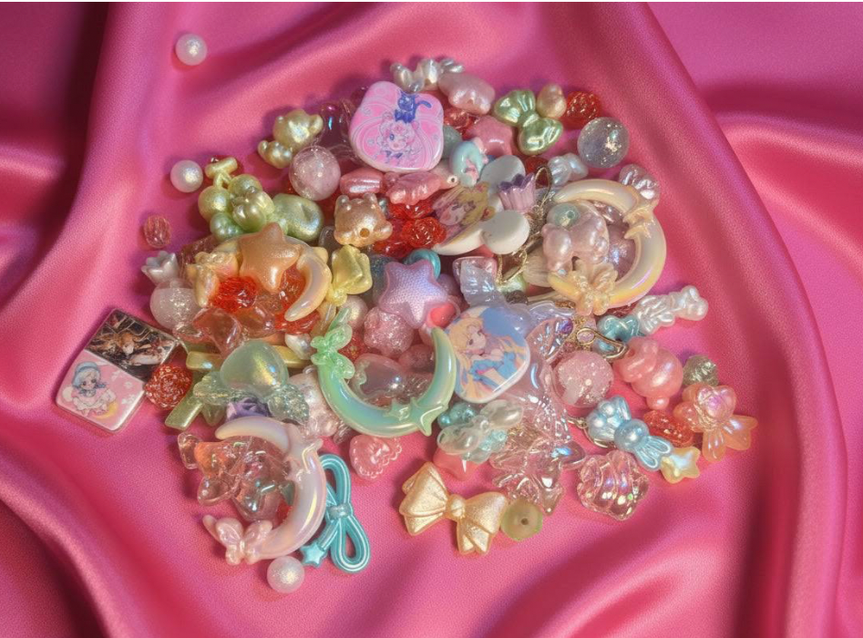 Pastel beaded charms, moon, star, and bow beads for DIY jewelry making on pink satin