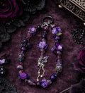 Purple beaded necklace with floral charms and bat pendant, handmade DIY accessory on velvet