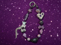 Handmade beaded charm bracelet with heart, star, and bear charms on purple glitter background