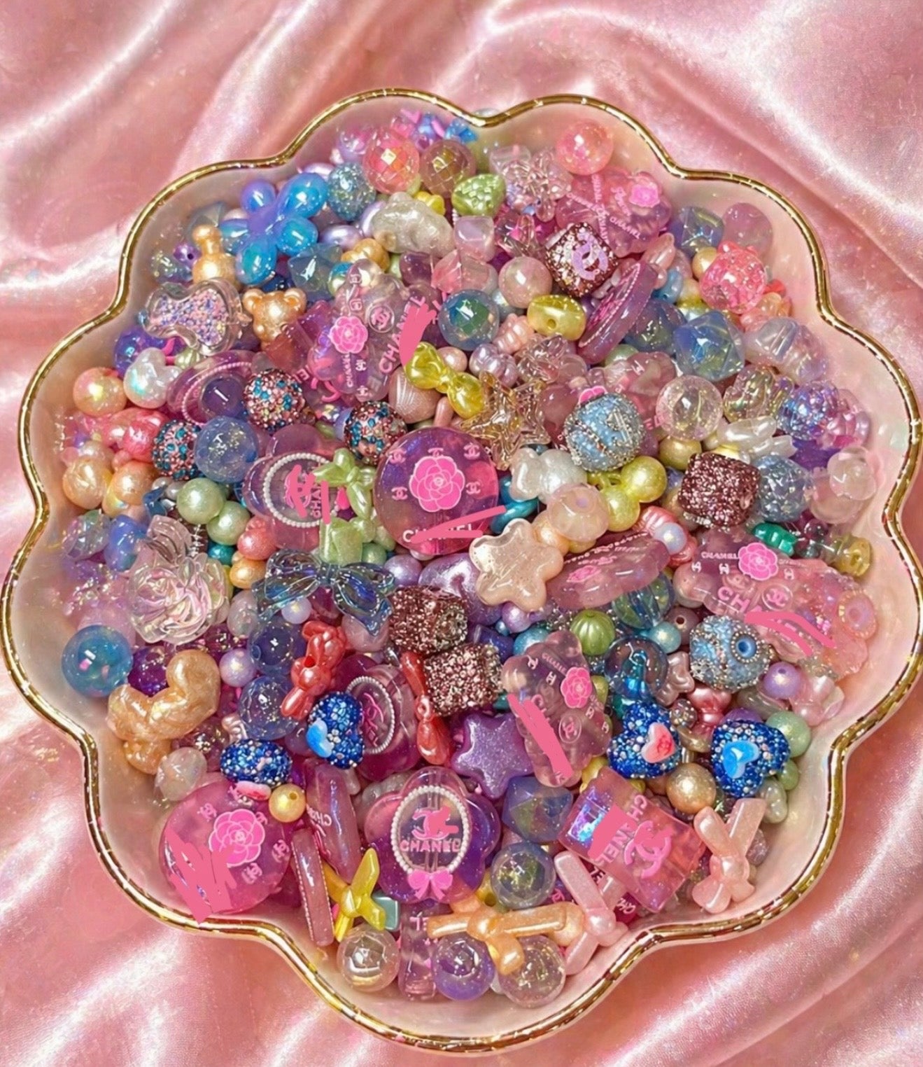 Colorful handmade beads and charms in a floral dish, perfect for DIY jewelry and craft supplies.